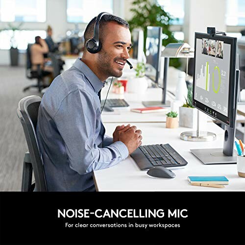 Office worker wearing a headset using a computer with a noise-cancelling microphone.